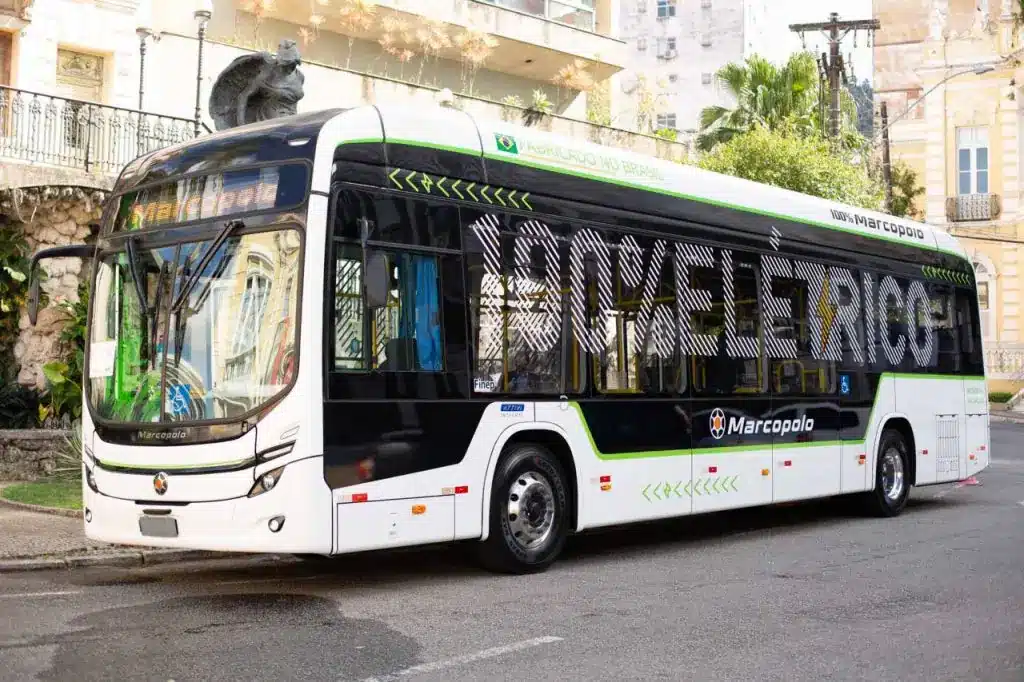 The image shows a white electric bus with a large design on the side that reads "1ßß% eletrico"